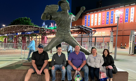 Five conference attendees sitting in front of a baseball stadium