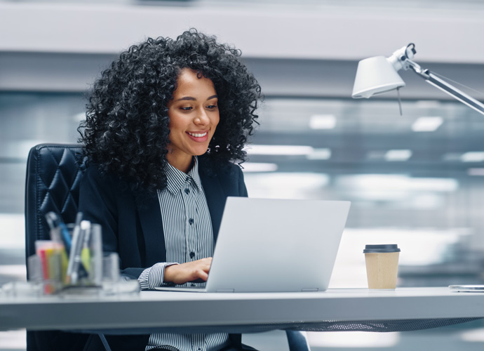 Business woman at a desk typing on a laptop computer