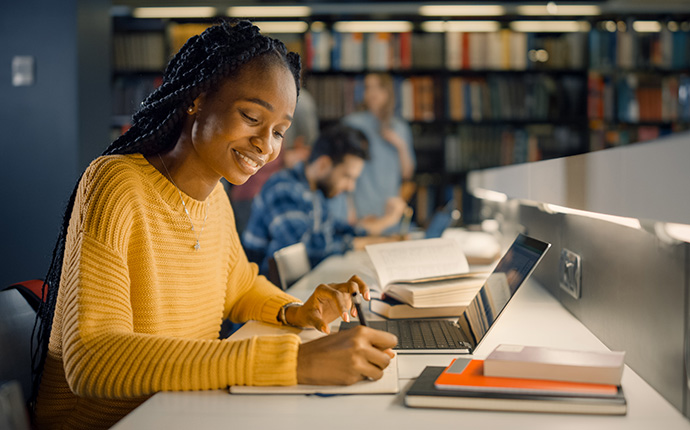 student taking notes and studying in the library