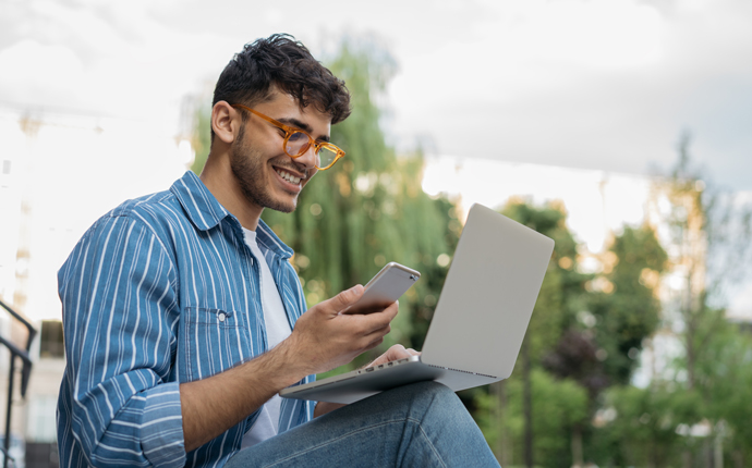 student using a smartphone and laptop computer