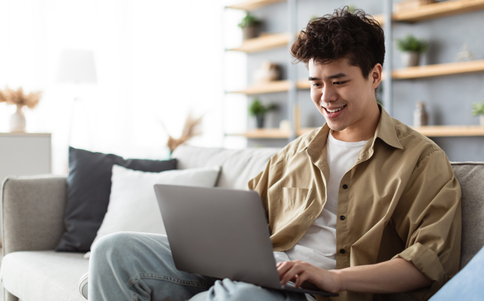 young person sitting on a couch and using a laptop computer